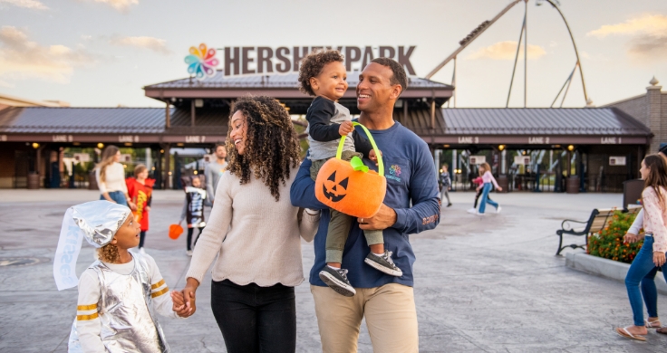 Family with two small children walking into Hersheypark Halloween dressed in costumes.