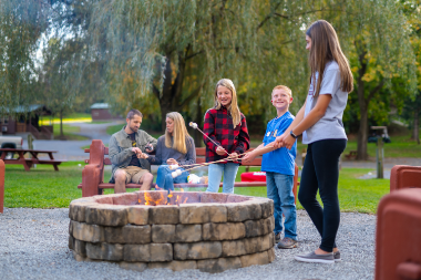 Family with three children making s'mores by the firepit at the Hersheypark Camping Resort. 