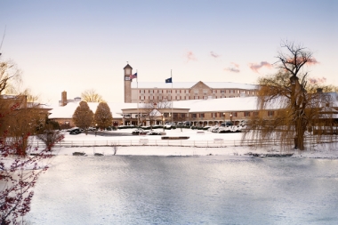 Exterior photo of the front of the Hershey Lodge on a winter day with a reflection of the lodge in the water.