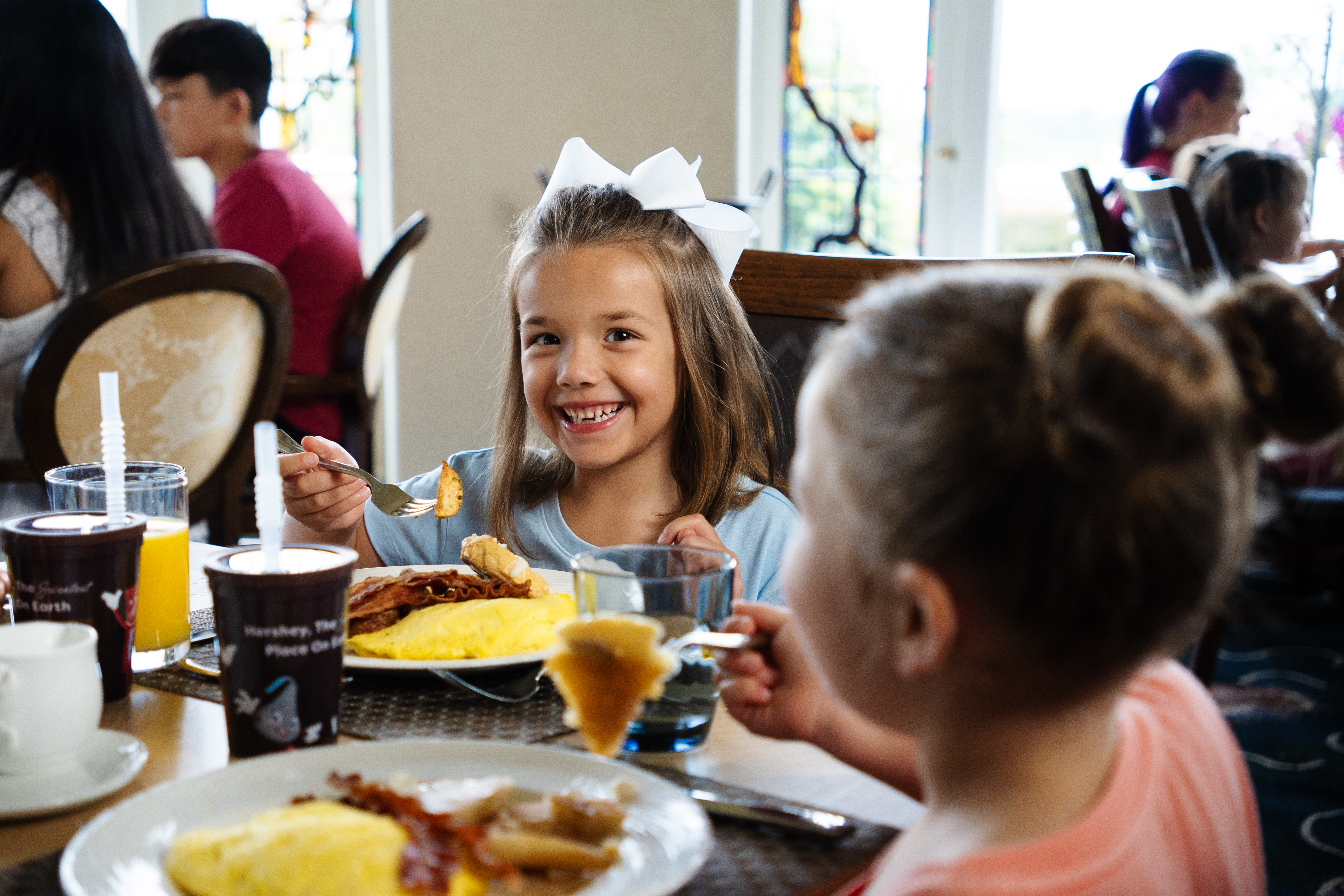 Little girl smiling while holding her fork and eating breakfast at The Circular.